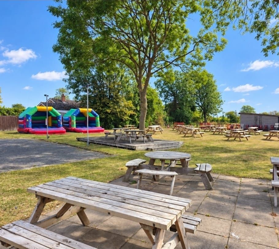 The beer garden with wooden picnic benches and bouncy castles on a sunny day