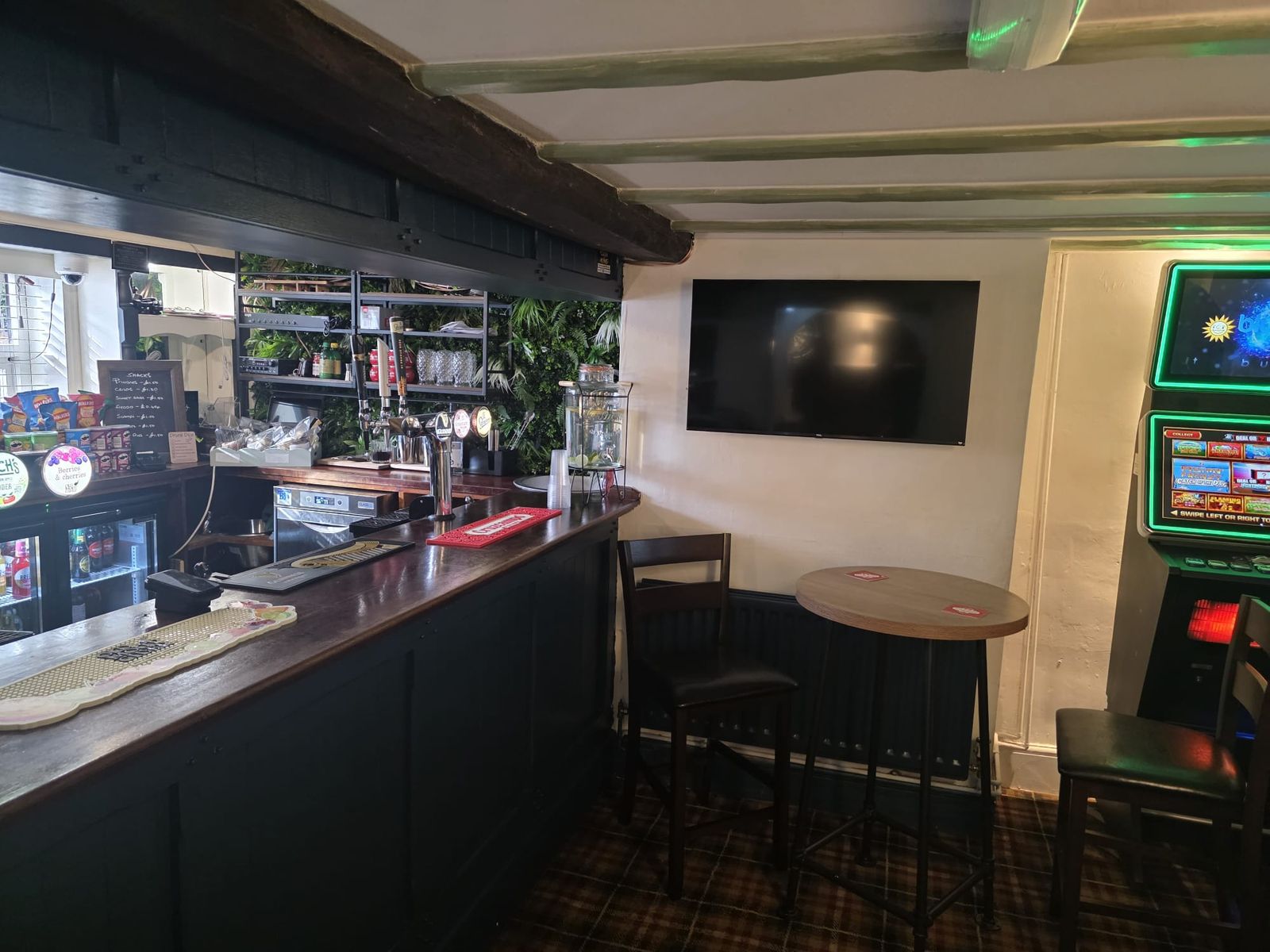 The bar with beer taps, a snacks board and a wall-mounted TV